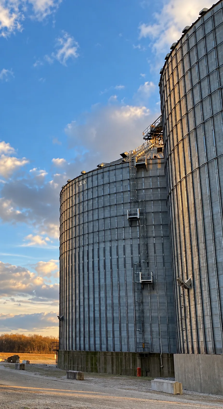 Grain storage bins under a blue sky.