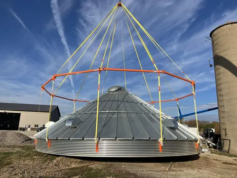 Bin Halo rigging system lifting a grain bin roof with orange lifting frame and yellow straps